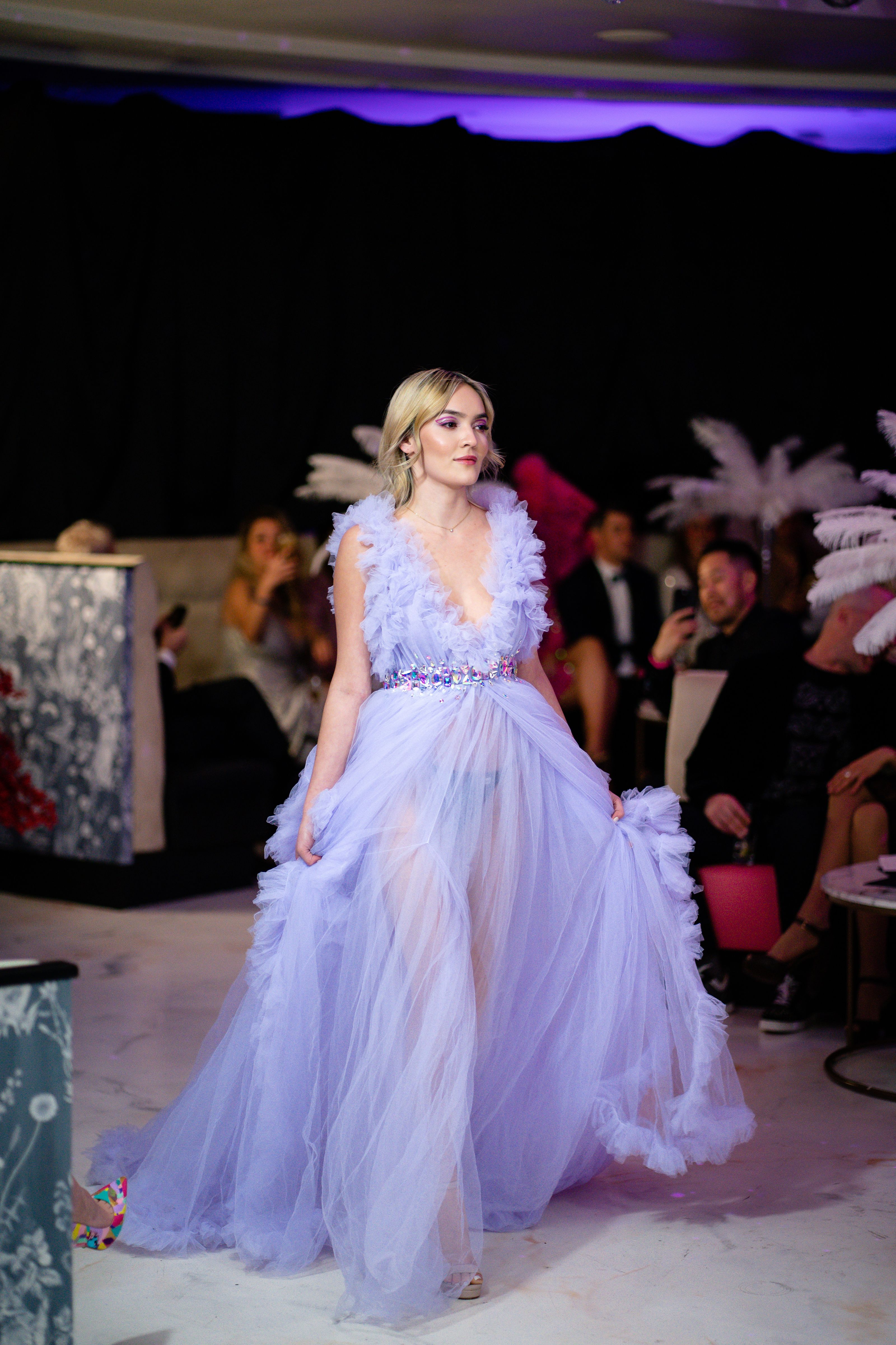 Uma modelo estilosa com cabelo loiro desfila em um impressionante vestido roxo durante um desfile de moda.