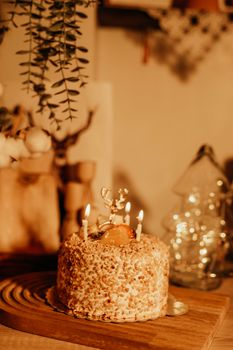Close-up of a rustic birthday cake with candles lit, set in warm ambient lighting.