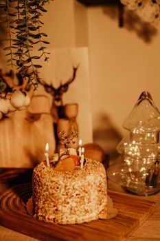 Close-up of a decorative festive cake with candles in a warm, rustic indoor setting.