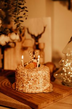 A beautifully decorated birthday cake with glowing candles in a warm, cozy indoor setting.