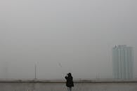 屋顶上的女人凝视着朦胧的城市天际线，它在雾霾中若隐若现，营造出一种宁静的氛围