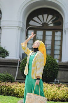 A woman in colorful traditional attire poses outdoors in Bandung, Indonesia, on a sunny day.