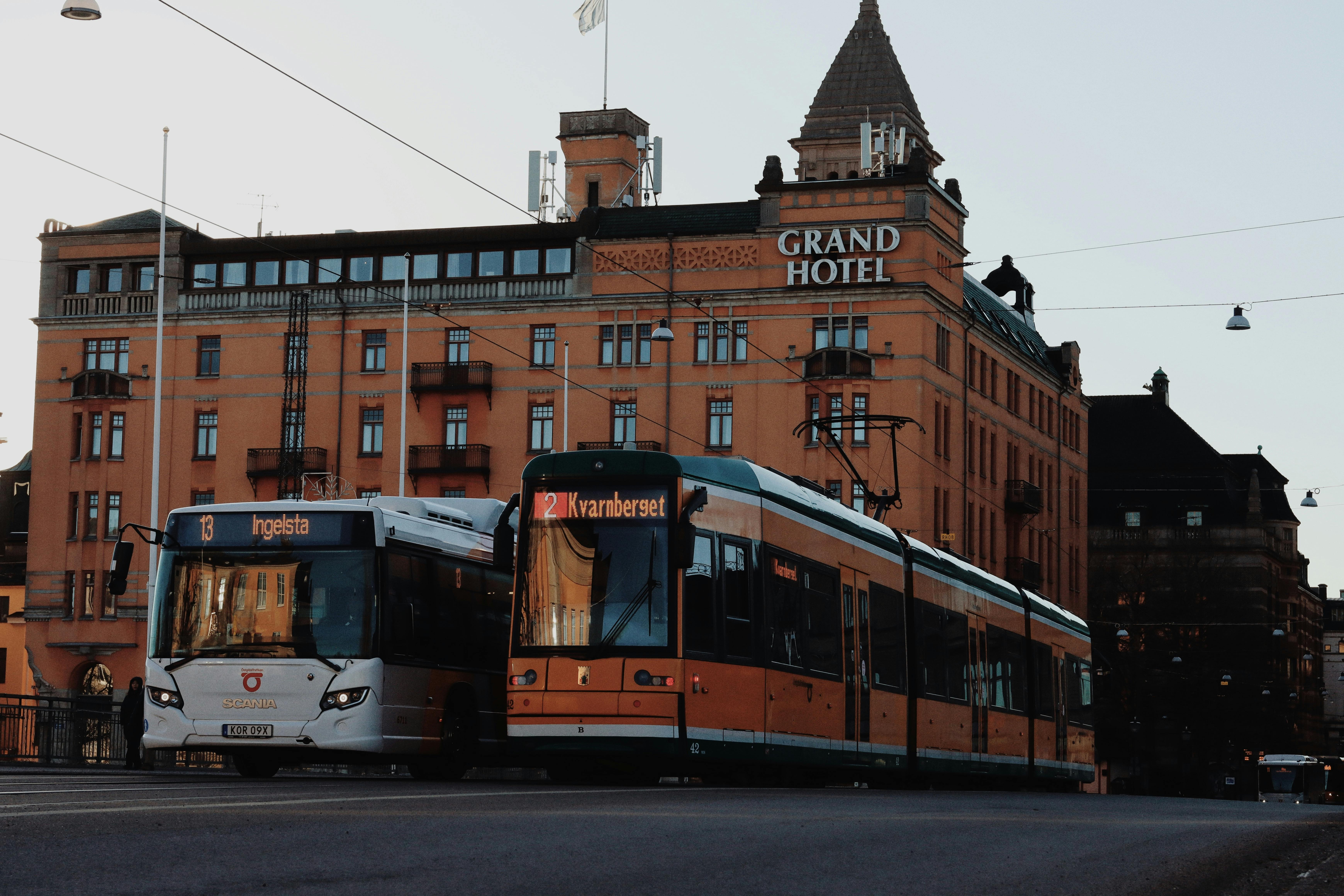 Street view featuring a bus and cable car in front of the Grand Hotel, Norrköping, Sweden.
