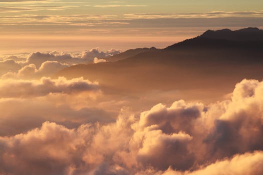 A breathtaking view of a sunrise over clouds with mountain silhouettes.