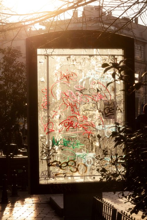Free A bus shelter covered in colorful graffiti, captured in the warm glow of sunset in an urban city setting. Stock Photo