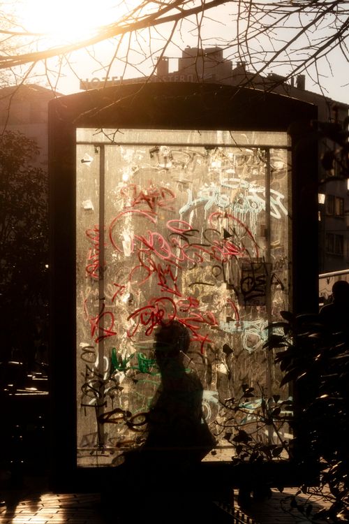 Free Silhouette of person in graffiti-covered booth at sunset, capturing urban artistic vibe. Stock Photo