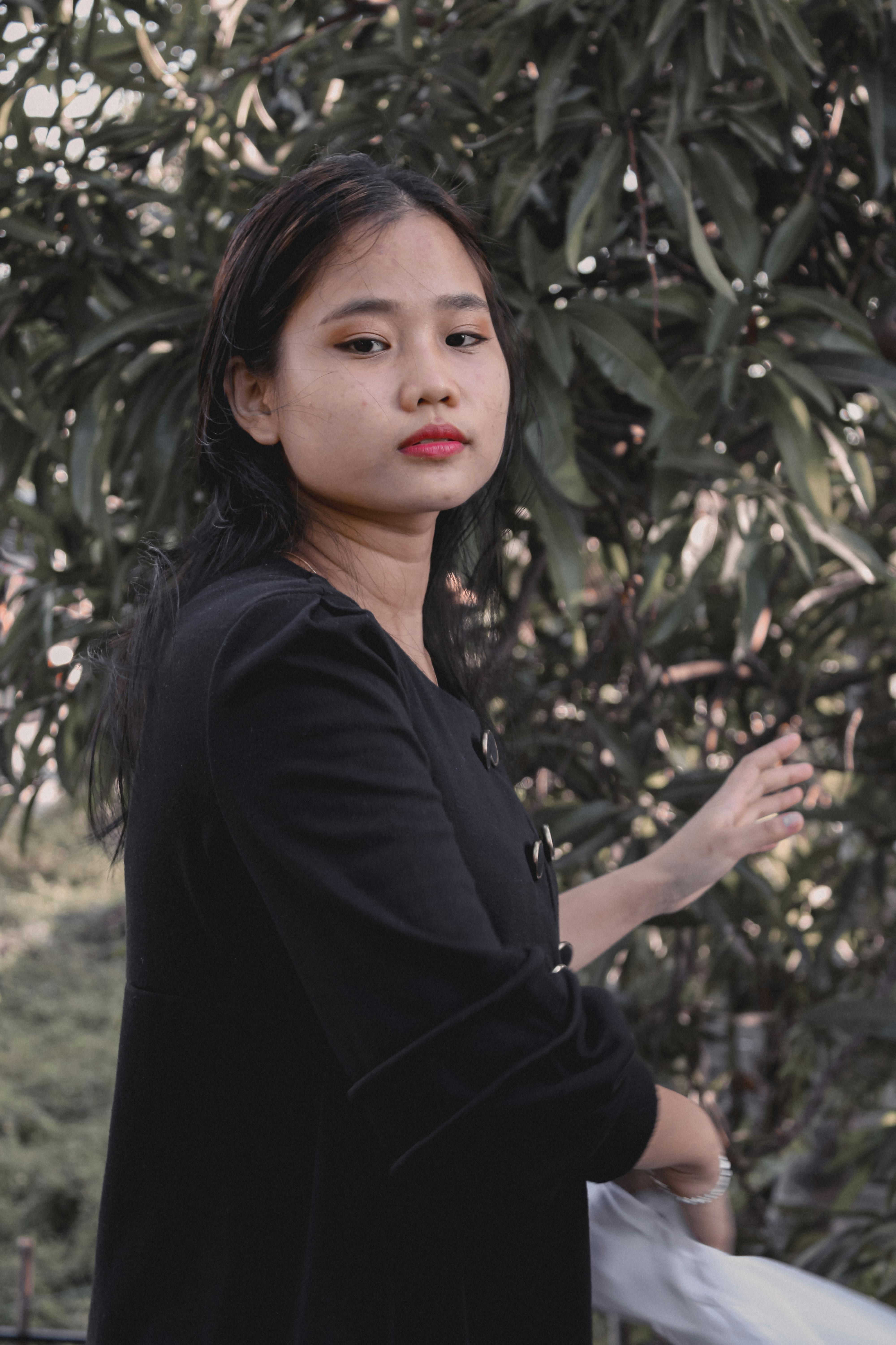 Elegantly dressed woman posing outdoors with a thoughtful expression.