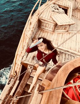 A woman reads a book on a rustic wooden sailboat, embracing a peaceful ocean voyage.