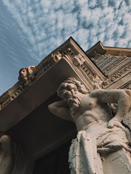 Free Low-angle view of a sculpture on a Renaissance-style building with a dramatic sky backdrop. Stock Photo