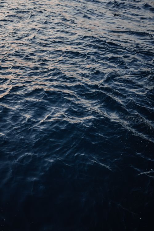 Free Gently rippling ocean waves at twilight capture a serene and moody atmosphere. Stock Photo