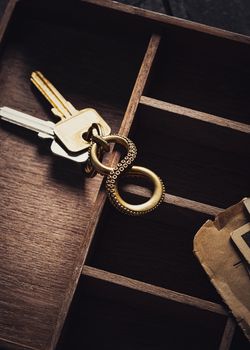 Close-up of keys with a metal keyring in a wooden drawer organizer.