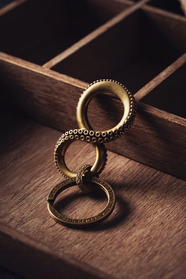 Brass octopus-tentacle keyring resting on a wooden surface — photo by COPPERTIST WU on Pexels
