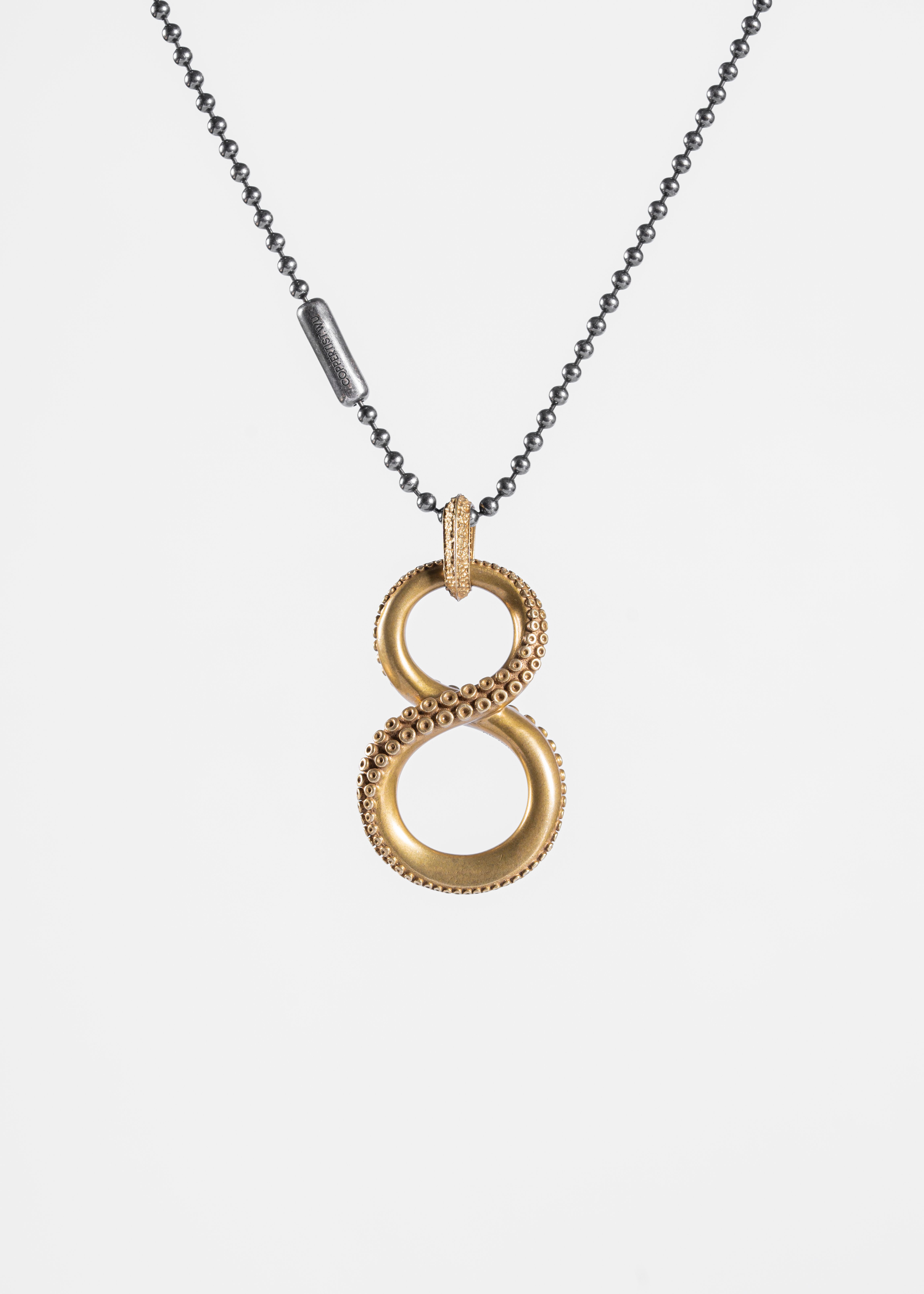 Stylish gold infinity pendant necklace with bead chain on a white background.