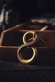 Close-up of a decorative golden octopus tentacle keychain on a wooden background.