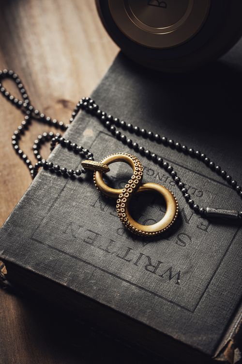 Free A gold infinity necklace rests on an antique book, showcasing elegance and timeless style. Stock Photo