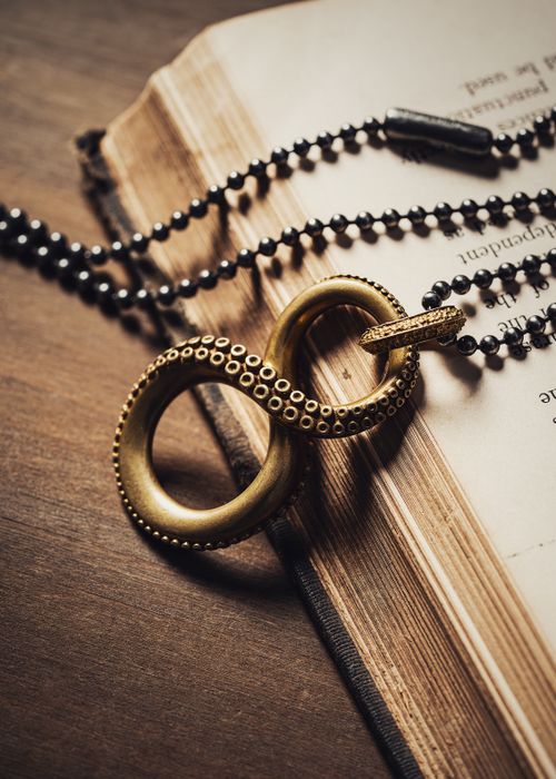 Free Close-up of a vintage brass necklace with beaded chain on an open book, featuring intricate detailing. Stock Photo