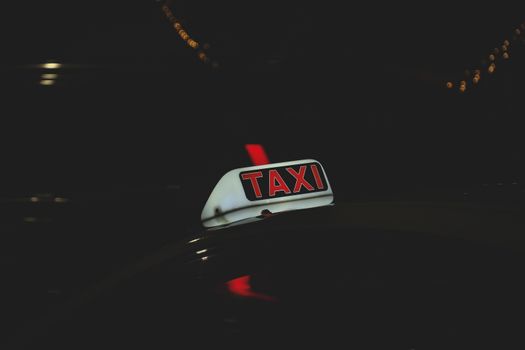 Illuminated taxi sign with light flare, captured in an urban night setting.