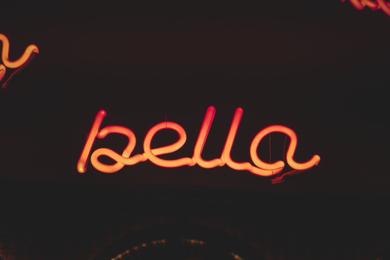 vibrant neon sign spelling bella glowing against a dark backdrop