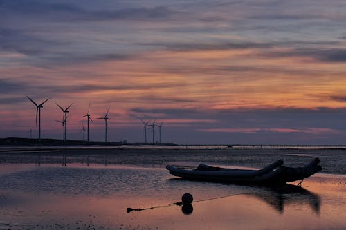 Free Windmills Behind Canoe Boat during Sunset Stock Photo
