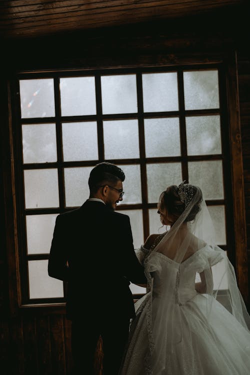 Back View of Newlyweds Standing near Window