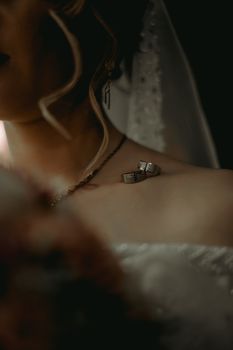 Close-up of a bride with wedding rings delicately placed on her collarbone, exuding elegance and romance.