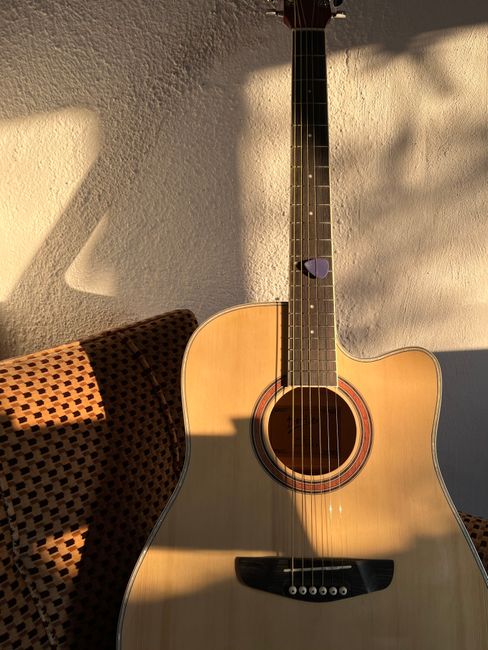 Acoustic guitar against sunlit wall in İstanbul, perfect for music themes.