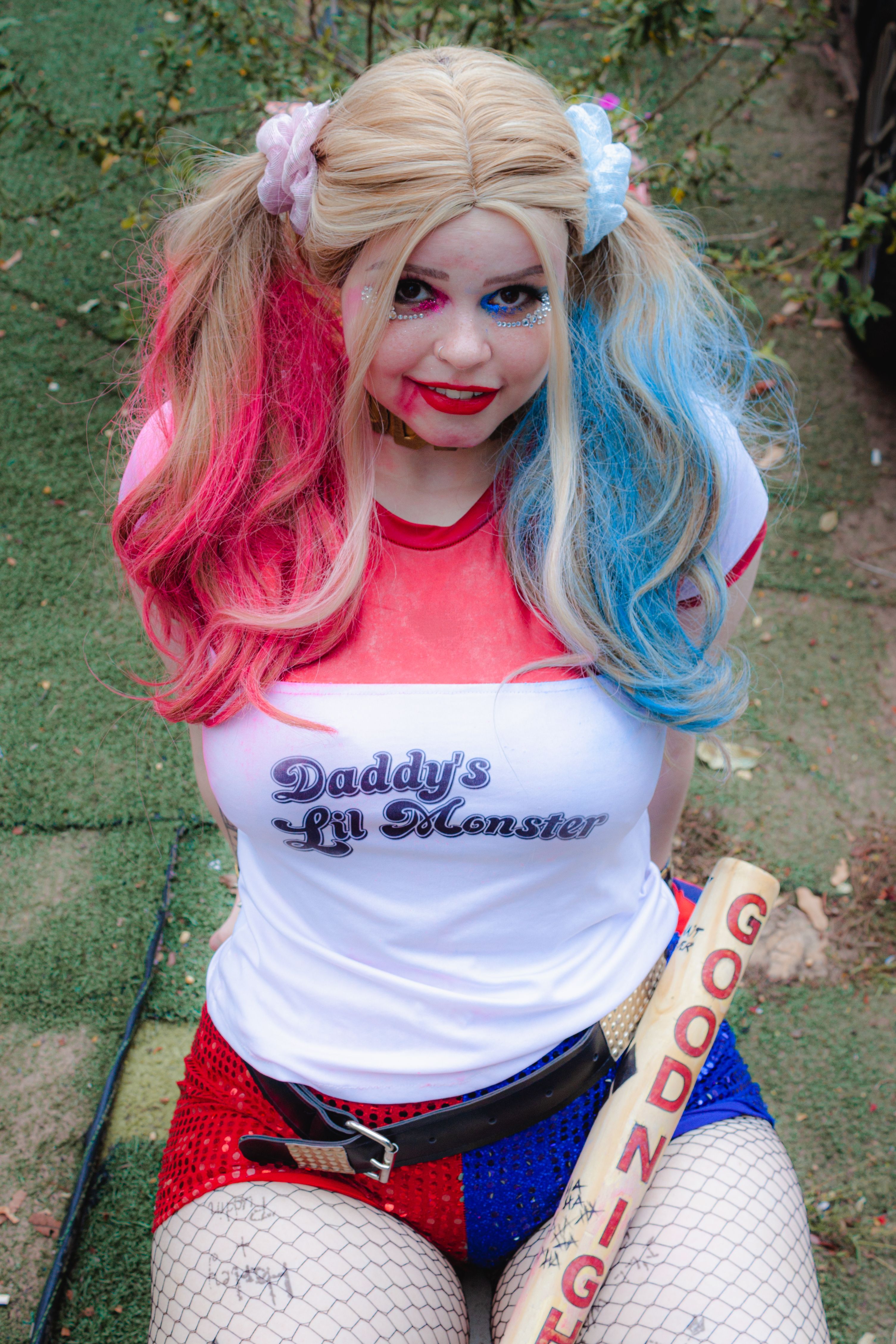 Vibrant cosplay of a popular comic book character posing outdoors with a baseball bat.