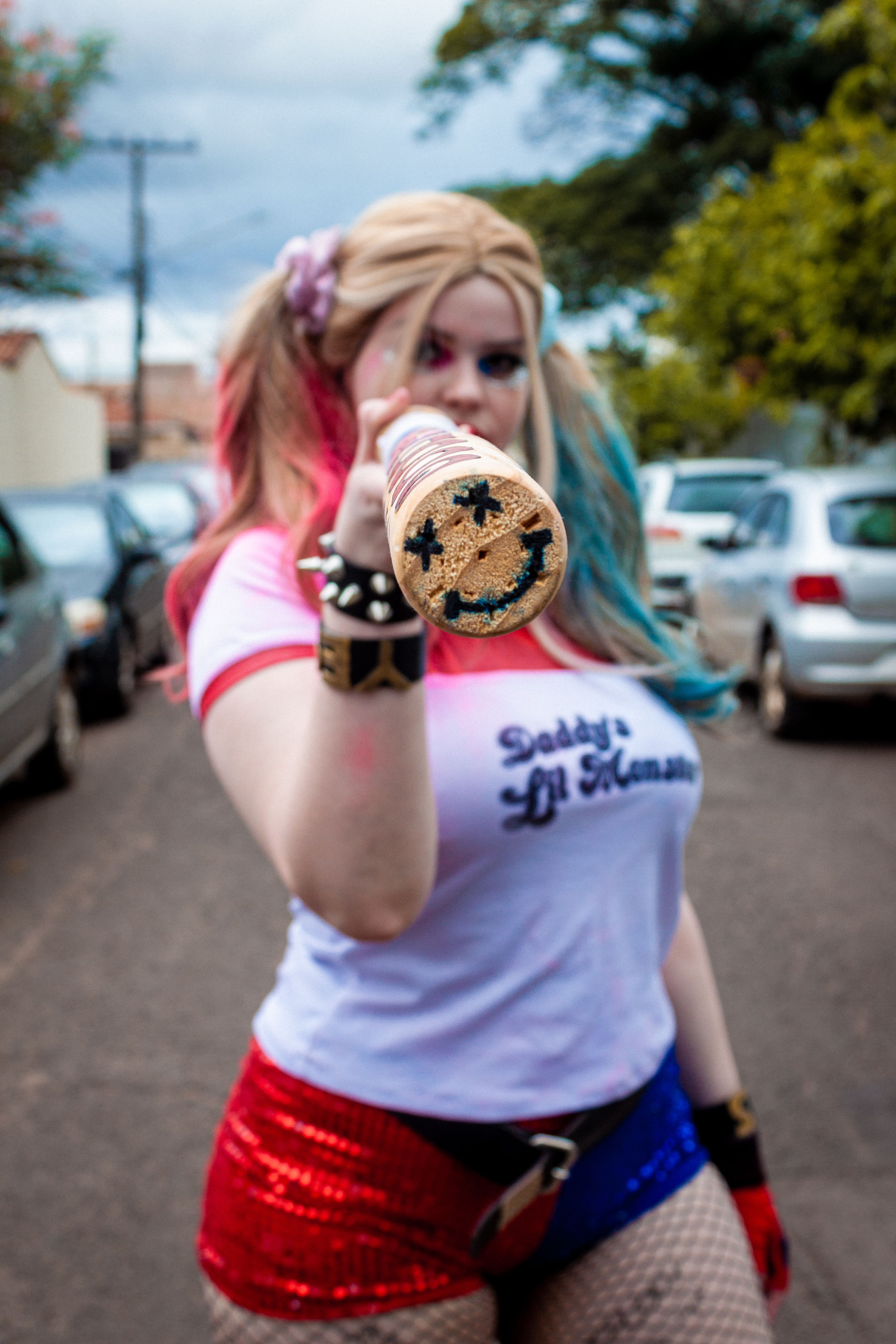 Dynamic Harley Quinn cosplay with a playful pose in an urban setting of Campo Grande, Brazil.