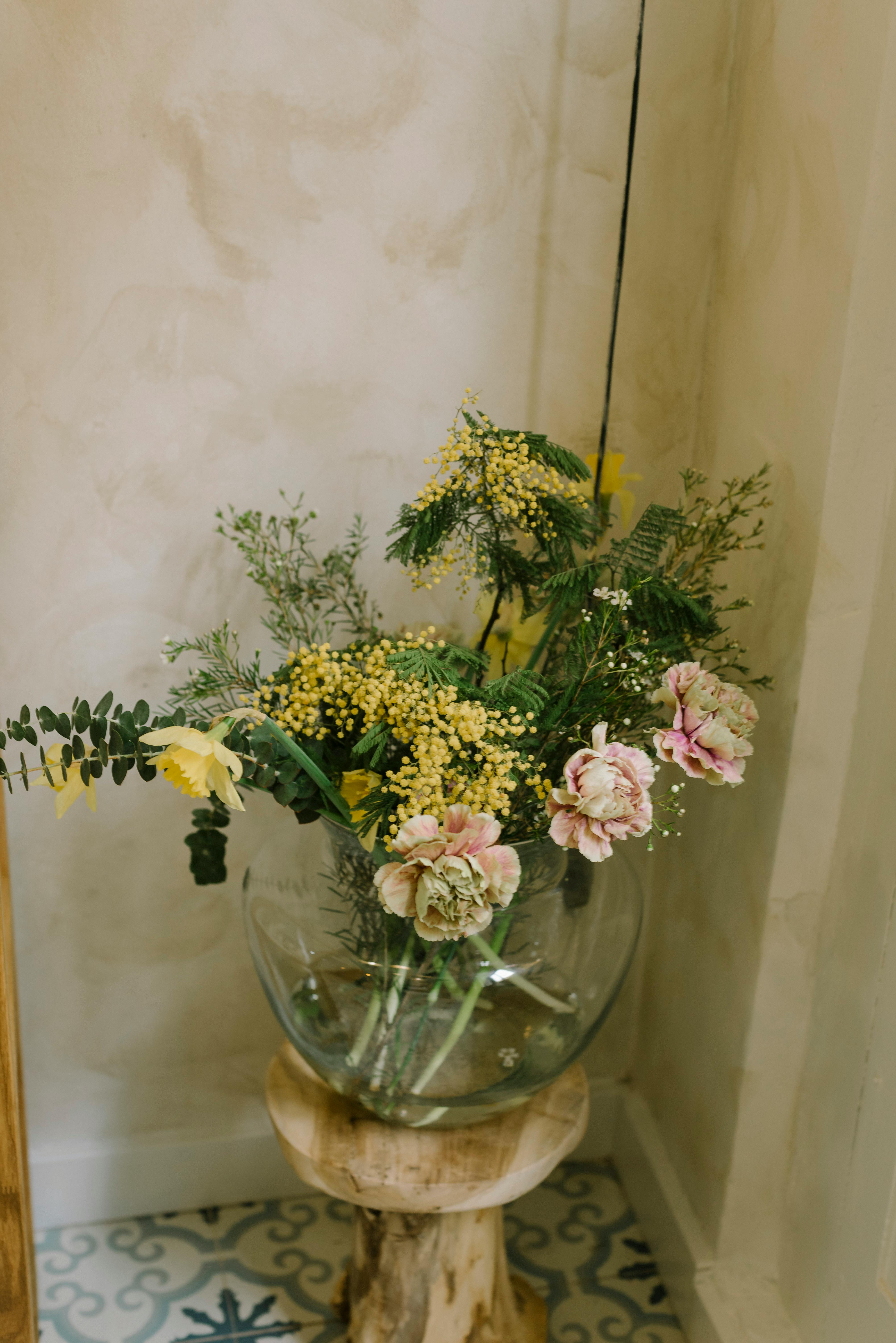 Charming floral composition in a glass vase on a wooden stool, captured indoors.