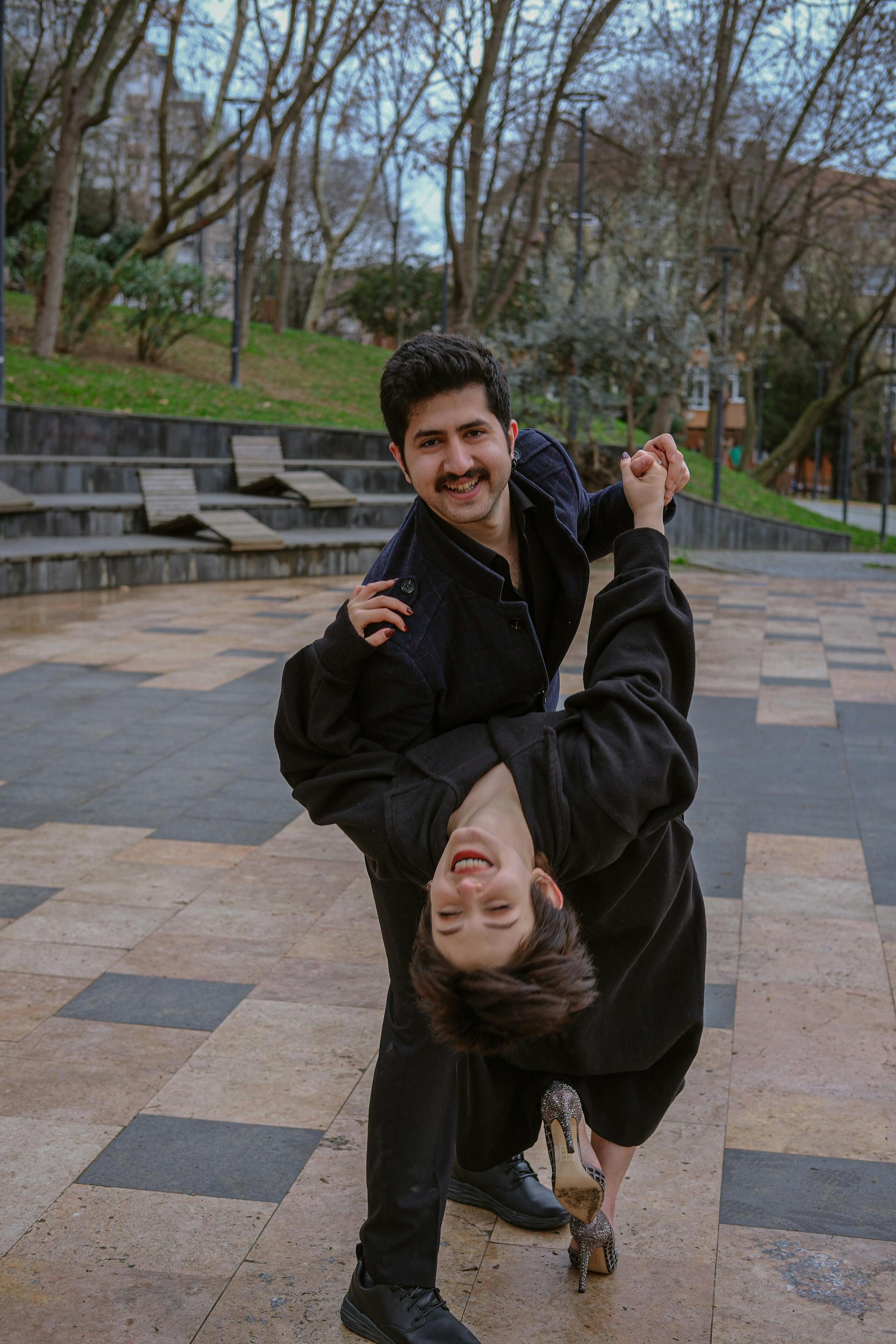 a man and woman are dancing together in a park