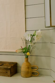 A minimalist flower arrangement in a rustic ceramic vase placed indoors, adding a serene touch of nature.