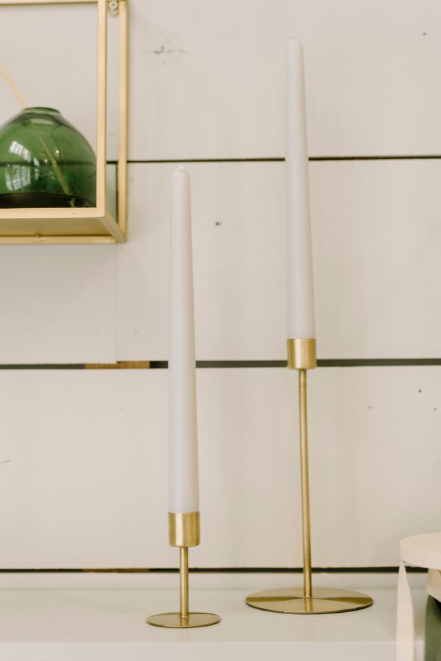 Brass candle holders with tapered candles on a white shelf — Alina Skazka on Pexels
