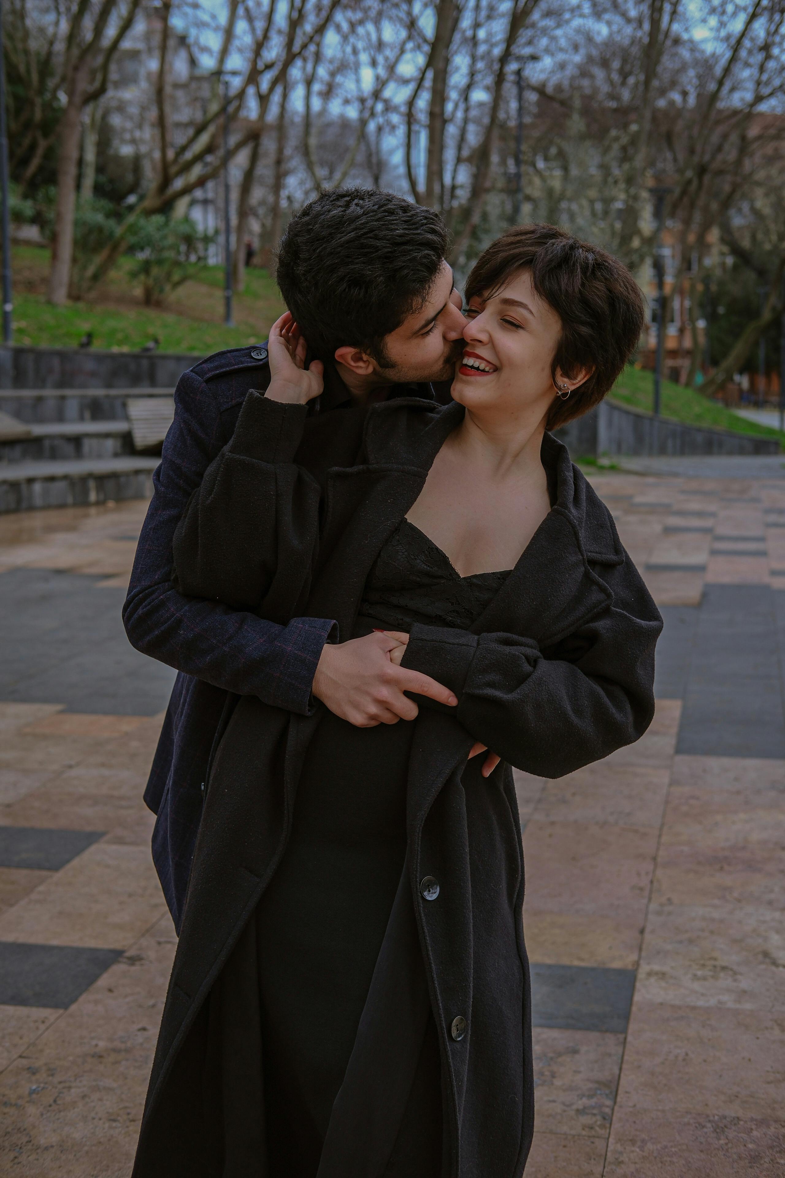 a man and woman are kissing in the park