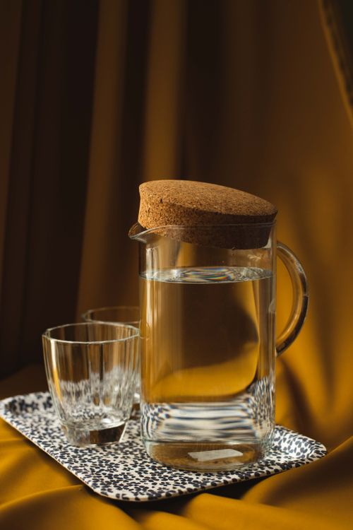 Free Stylish glass jug and cups on a decorative tray with a warm amber backdrop, evoking luxury and sophistication. Stock Photo
