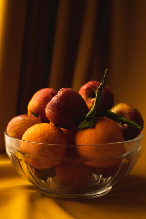 Free A vibrant and colorful still life depicting fresh oranges and peaches in a glass bowl. Stock Photo