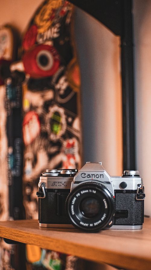 Free Close-up of a classic film camera on a wooden shelf with a blurred artistic background. Stock Photo