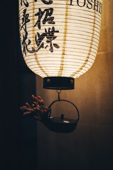 A traditional Japanese lantern illuminates a moody interior with flowers and a teapot accent.