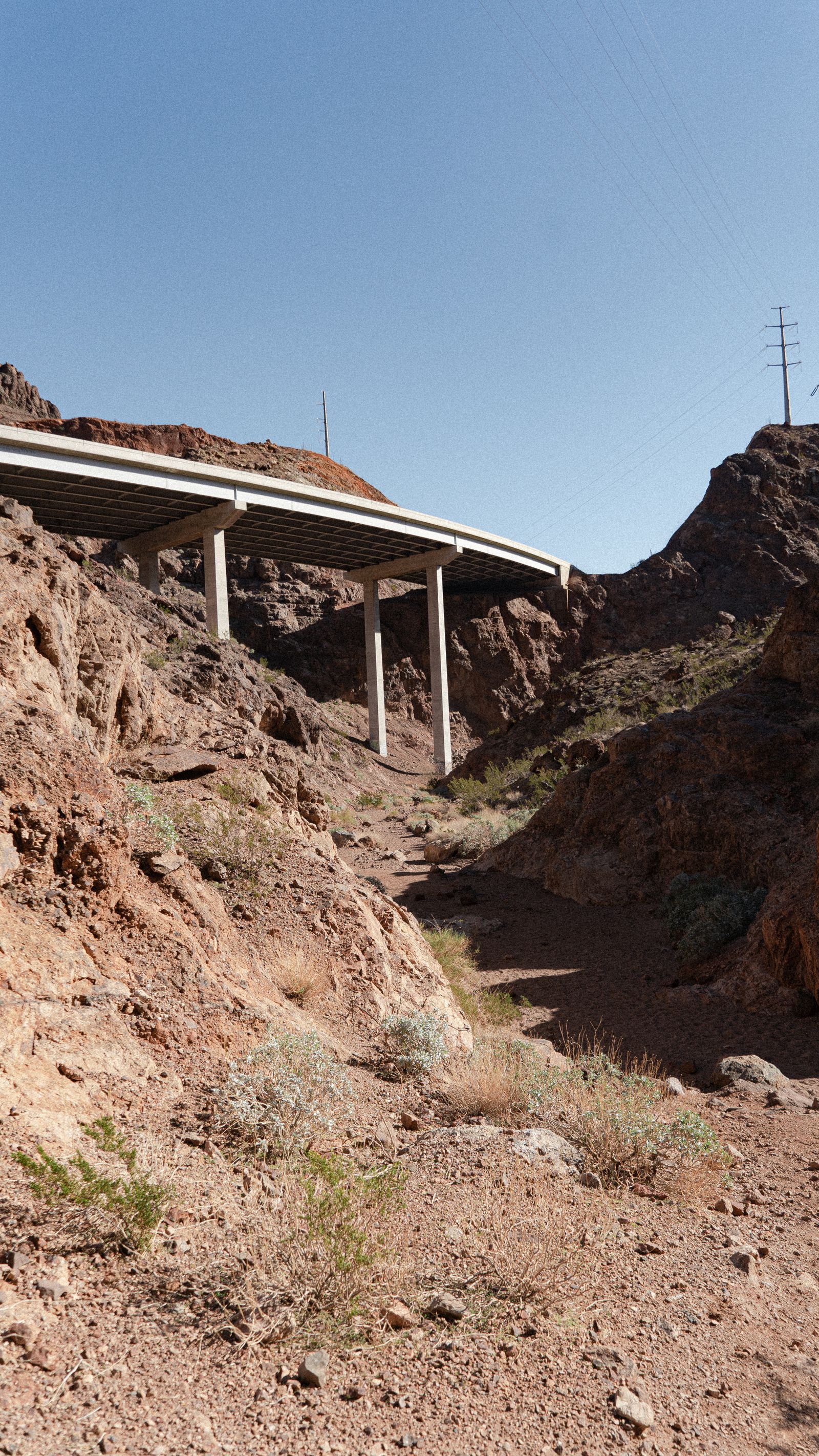 A solitary concrete bridge crossing a barren desert canyon under a clear blue sky