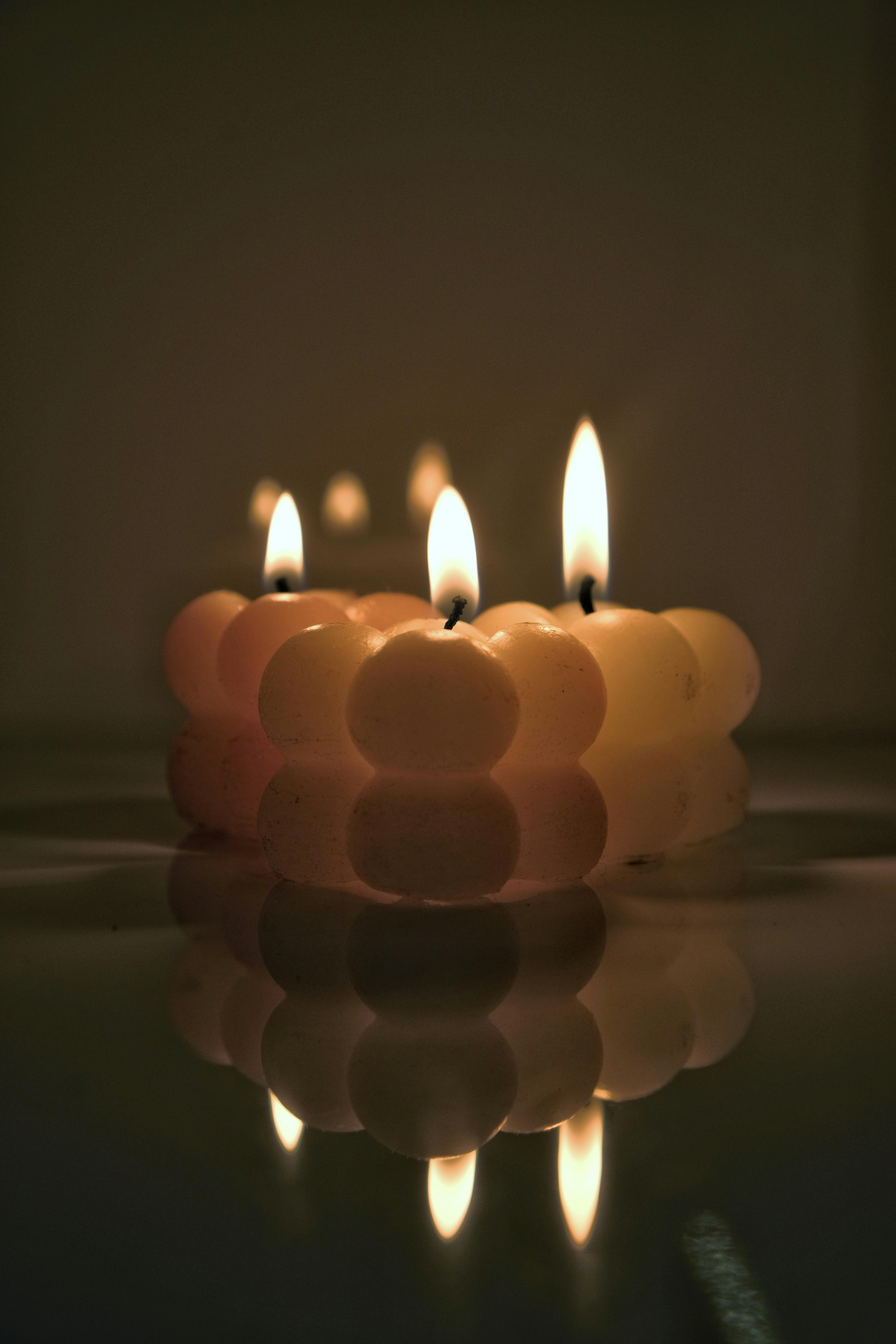 Bubble Shaped Candles Burning and Reflecting in a Wet Surface · Free
