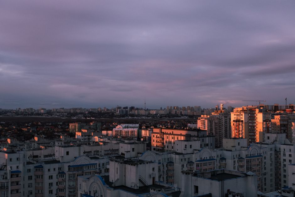 Aerial view of Kyiv city with striking clouds and sunset light over the urban skyline.