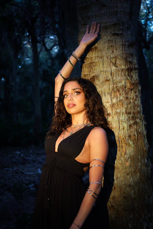 Young Beautiful Brunette Standing with Her Back against a Tree