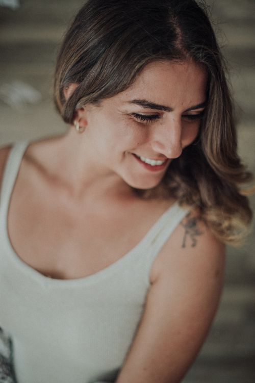 Free Charming portrait of a brunette woman smiling, captured indoors wearing a white tank top. Stock Photo