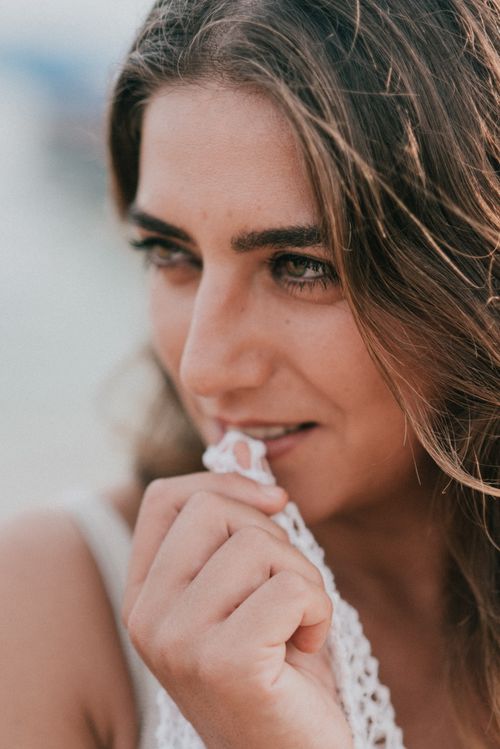 Free Close-up portrait of a woman biting lace, conveying beauty and contemplation. Stock Photo