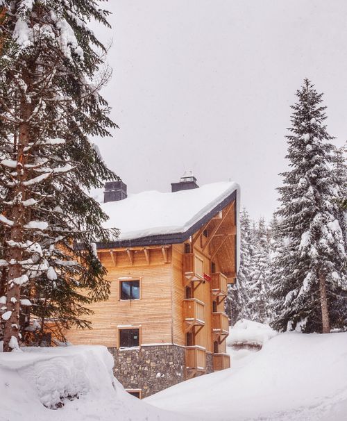Free A wooden chalet in a snowy forest setting, capturing winter's serene beauty. Stock Photo