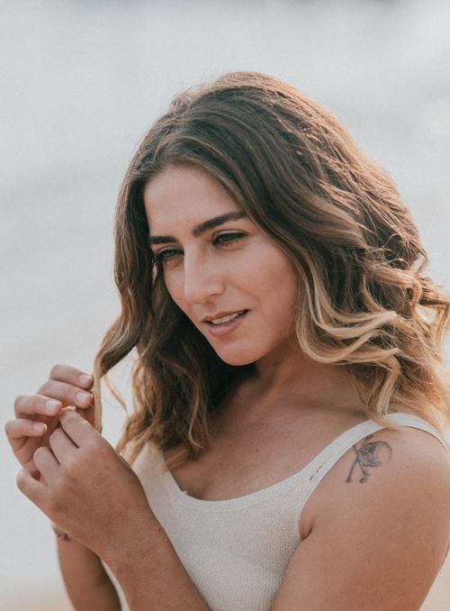 Free Portrait of a woman with wavy brown hair enjoying a sunny day outdoors. Stock Photo