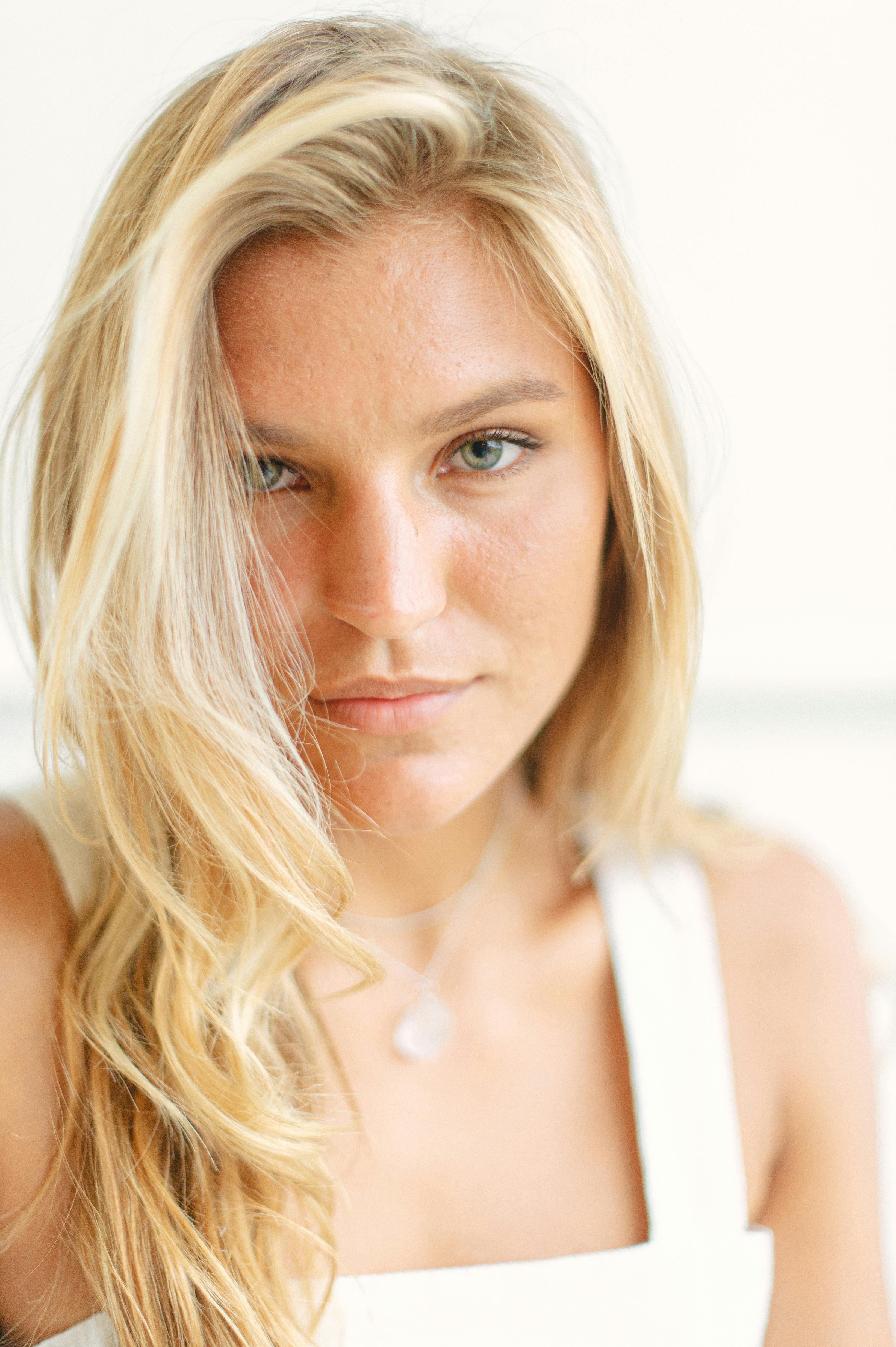 Close-up portrait of a blonde woman in white, exuding elegance and confidence.
