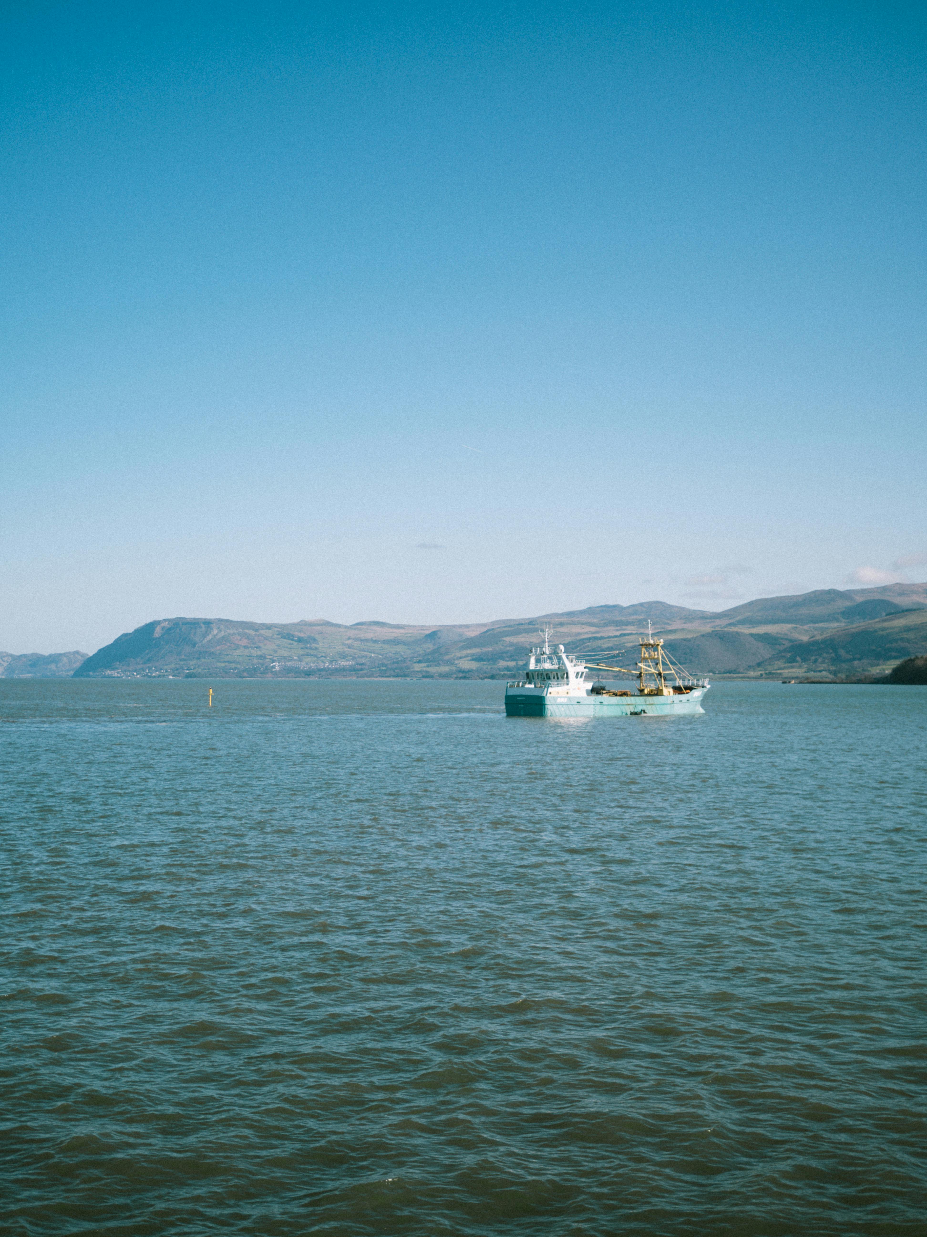 A tranquil scene of a boat sailing in the calm waters near Bangor, Wales.