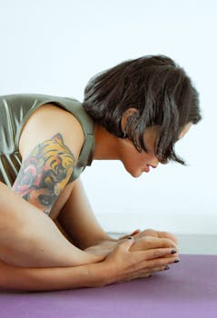 Woman with tiger tattoo doing yoga pose indoors on mat.