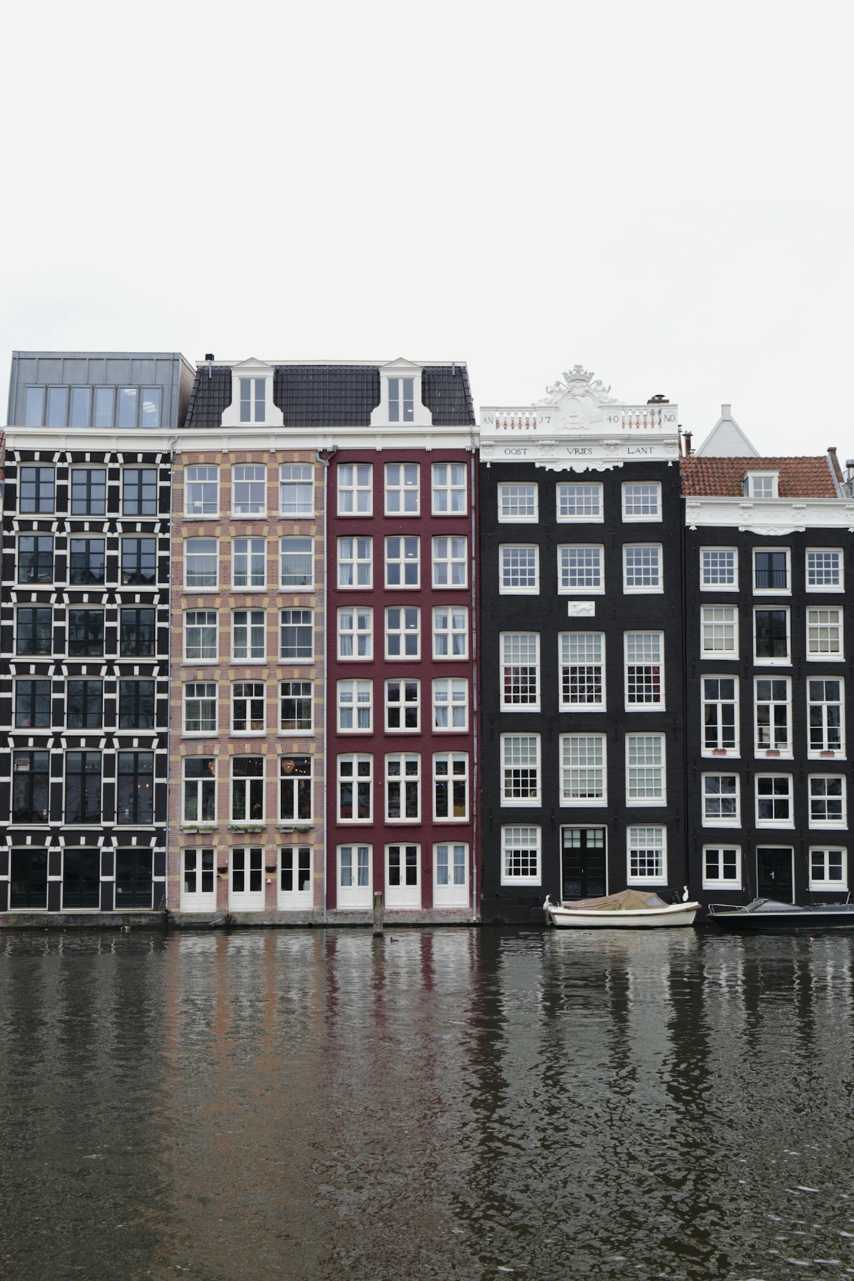 Traditional canal houses in Amsterdam reflecting on water, showcasing Dutch architecture.