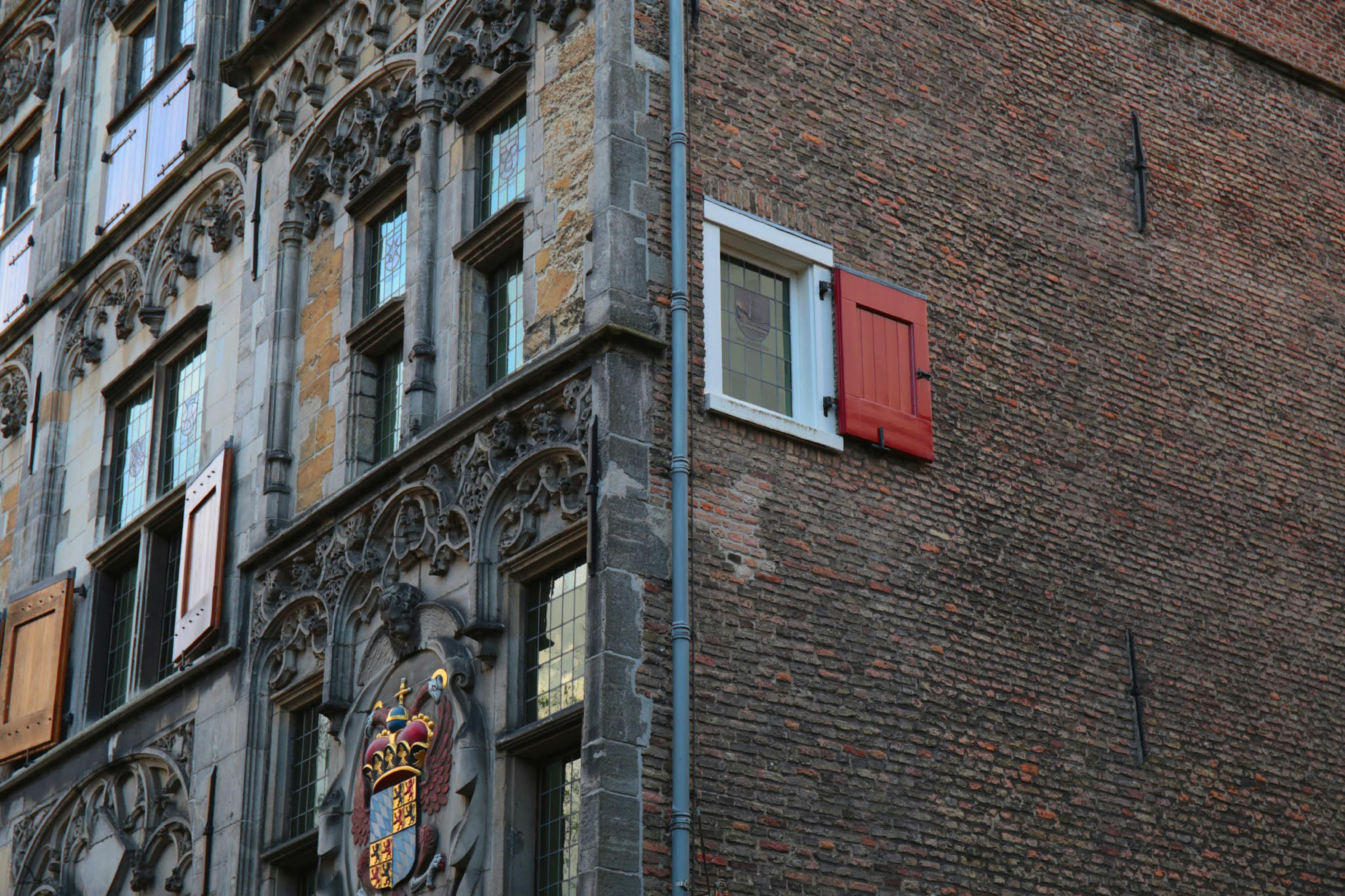 Close-up of a historic building's facade with ornate stonework and red shutters.